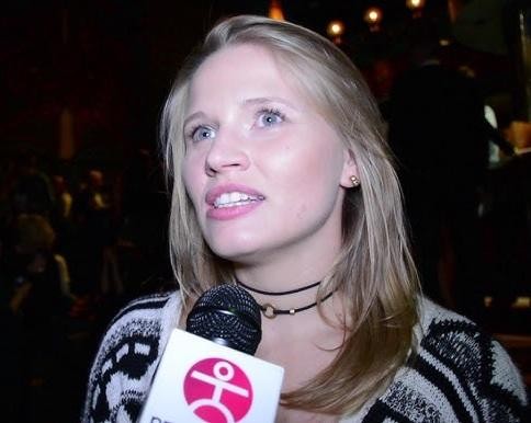 Natalia Rybicka na scenie teatralnej, uchwycona w dynamicznej pozie podczas występu, z intensywnym oświetleniem scenicznym.