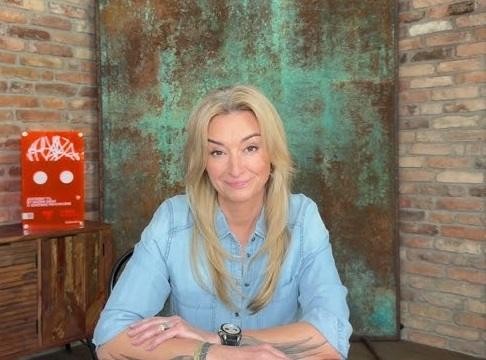 Martyna Wojciechowska w podróżniczym stroju na tle egzotycznego krajobrazu, symbolizującym jej program