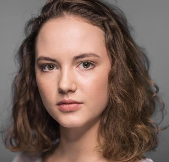 Martyna Byczkowska w stroju absolwenta Akademii Teatralnej, symbolizująca jej sukces edukacyjny i nagrodę Rektora, z widocznym dyplomem.