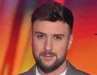Aleksander Sikora, prezenter telewizyjny, w trakcie prowadzenia programu na żywo, z uśmiechem i gestykulacją, symbolizujący dynamikę jego kariery medialnej.