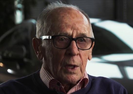 Samochód rajdowy Porsche 911 prowadzony przez Sobiesława Zasadę na tle zakurzonego toru rajdowego.