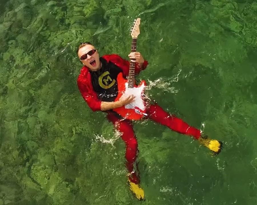 Czadoman podczas energicznego występu na scenie, śpiewający do mikrofonu, z publicznością w tle.